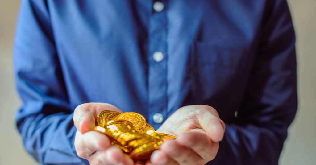 A person in a blue shirt holds a handful of shiny golden coins, symbolizing wealth and cryptocurrency.