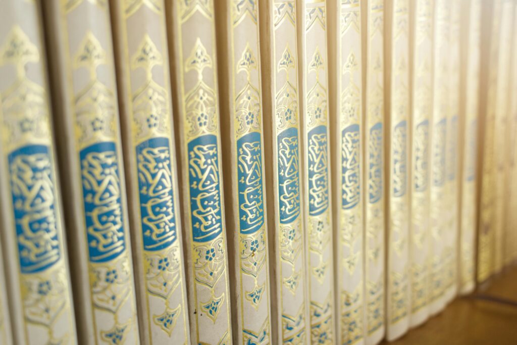 Close-up of beautifully crafted Quran books with intricate Arabic calligraphy on a shelf.