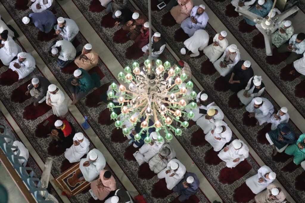 Aerial view of a diverse group of people praying in mosque, emphasizing unity.
